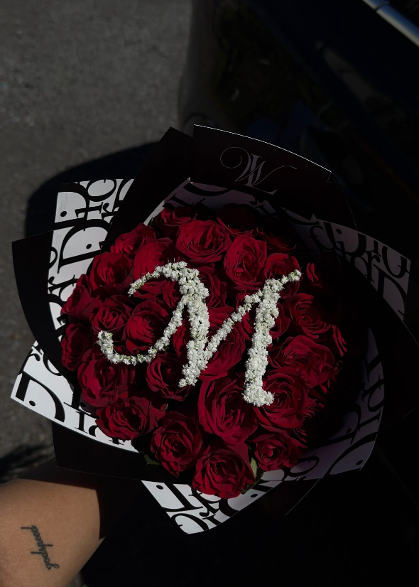 Bouquet of red roses with a white 'M' in a black holder.